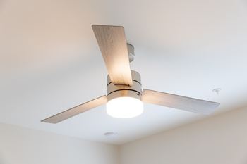 A ceiling fan with a light on in a room.